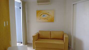 Una habitación con un sofá color crema, un cuadro de un ojo en la pared y una puerta con cortina.