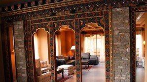 Une pièce avec un mur en pierre, un canapé, une table basse et un rideau à motifs.