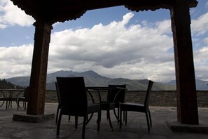 An outdoor seating area with tables and chairs, overlooking a mountainous landscape. - Naksel Boutique Hotel & Spa (Paro)