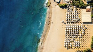 An aerial view of a beach with rows of umbrellas and sun loungers, a sandy shore, and the ocean. - Royal Garden Beach Hotel - All Inclusive (Alanya)