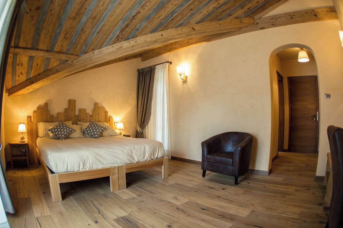 Una camera da letto con un letto in legno, una sedia, un comodino e una lampada.
