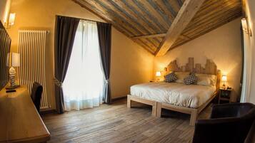 Quarto com teto de madeira, uma cama com almofadas, uma cadeira, uma escrivaninha e um abajur.