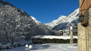 Paisatge de muntanya cobert de neu amb un edifici que presenta parets de pedra i façana de fusta.
