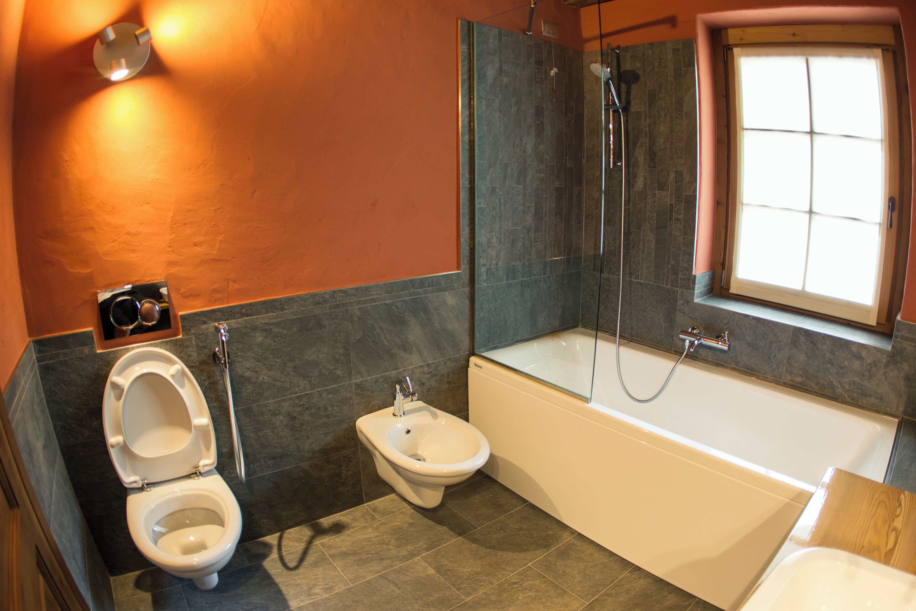 A modern bathroom with a toilet, bidet, and bathtub.