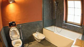 A modern bathroom with a toilet, bidet, and bathtub.