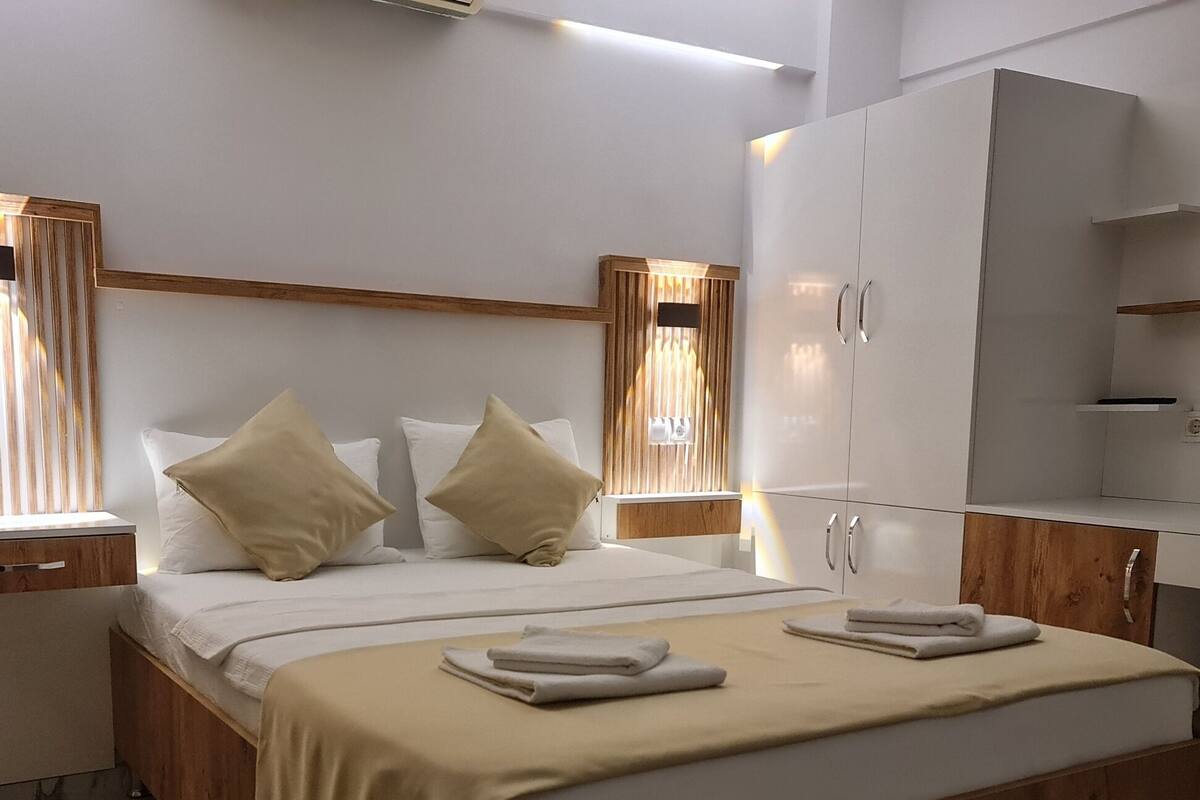 Un dormitorio moderno con estructura de cama de madera, ropa de cama blanca y un amplio armario.