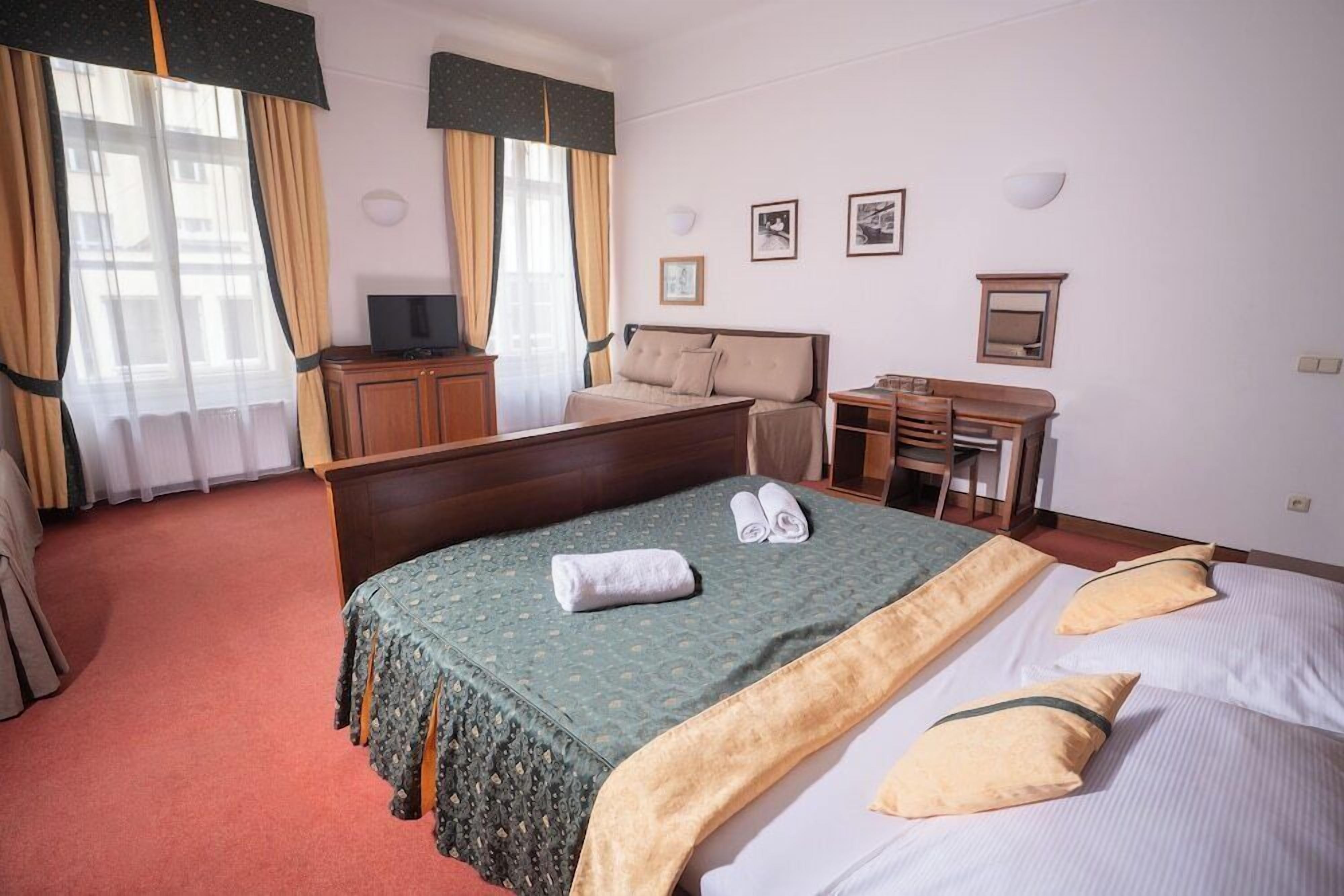 Ein Hotelzimmer mit einem großen Bett, einem Schreibtisch, einem Stuhl, einem Fernseher und einem Kleiderschrank.