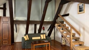 A cozy room with a wooden staircase, a green sofa, and a wooden coffee table. - U Medvidku (Prague)