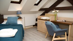 A bedroom with a bed, a desk, a chair, a lamp, and a radiator. - U Medvidku (Prague)
