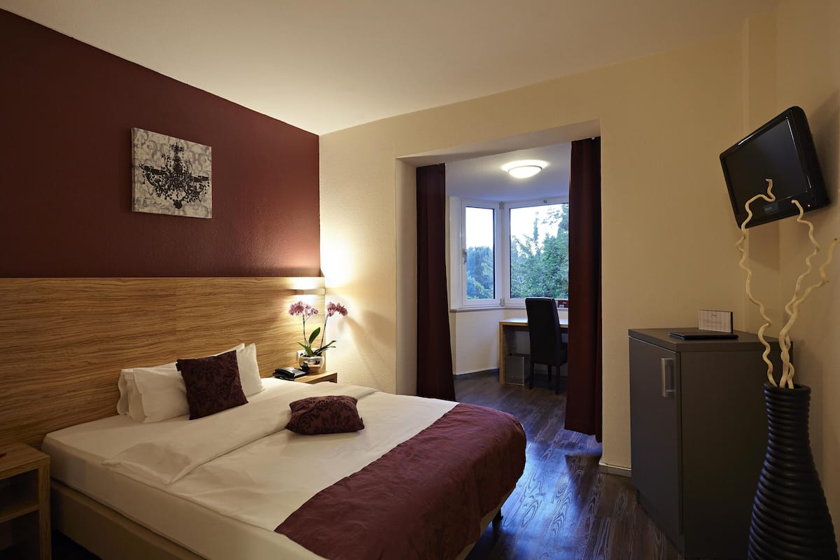 Une chambre d’hôtel avec un grand lit, un bureau, une télévision et une vue sur l’extérieur.