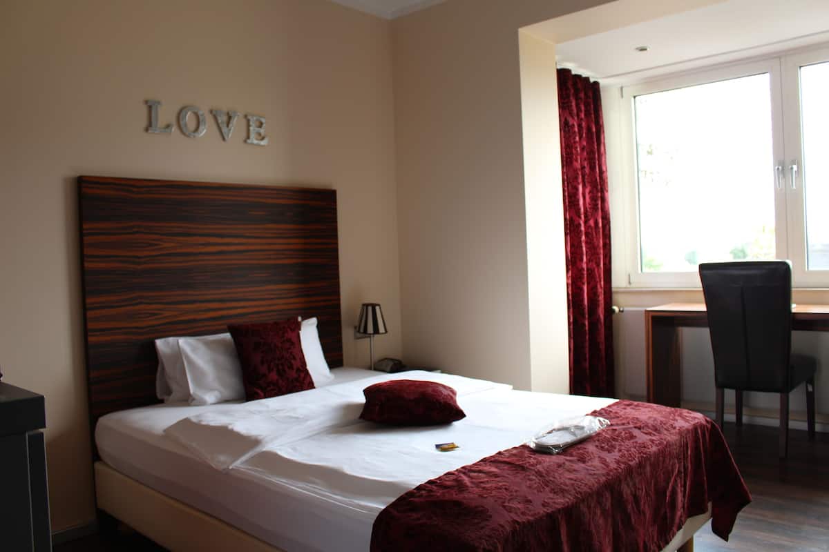 Une chambre d’hôtel avec un lit, un bureau et une chaise.