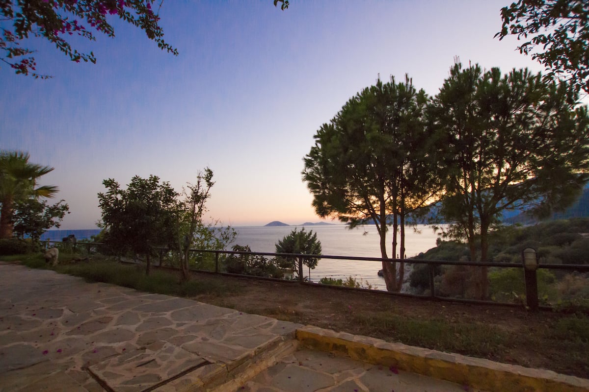 A stone pathway leading to a scenic overlook with a view of the sea and distant islands.