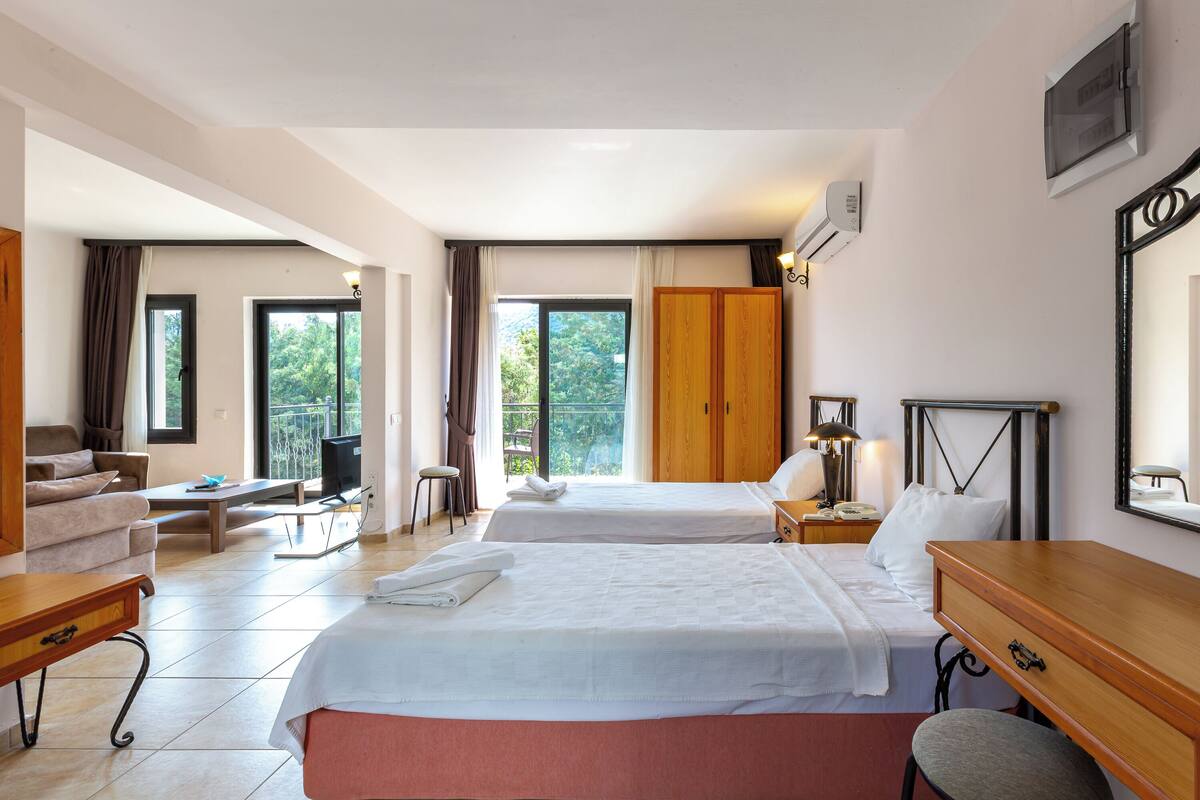 A hotel room with two beds, a desk, a chair, a TV, and a wardrobe.