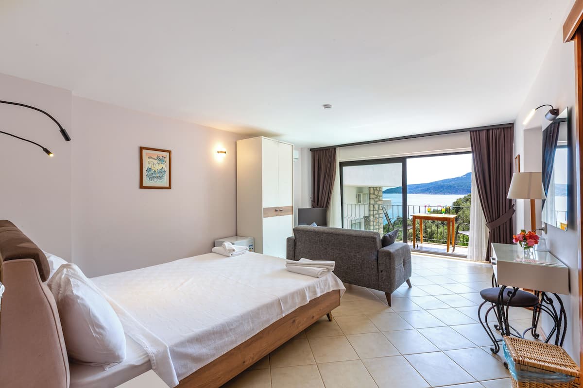 A hotel room with a bed, a sofa, a desk, and a balcony with a view.