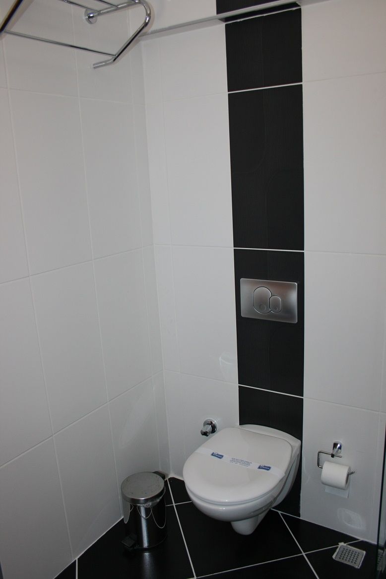 Un baño moderno con inodoro, bidé y un cesto de basura.