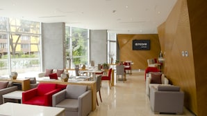 Un moderno vestíbulo de hotel con áreas de estar, una recepción y grandes ventanales que ofrecen vistas al exterior.