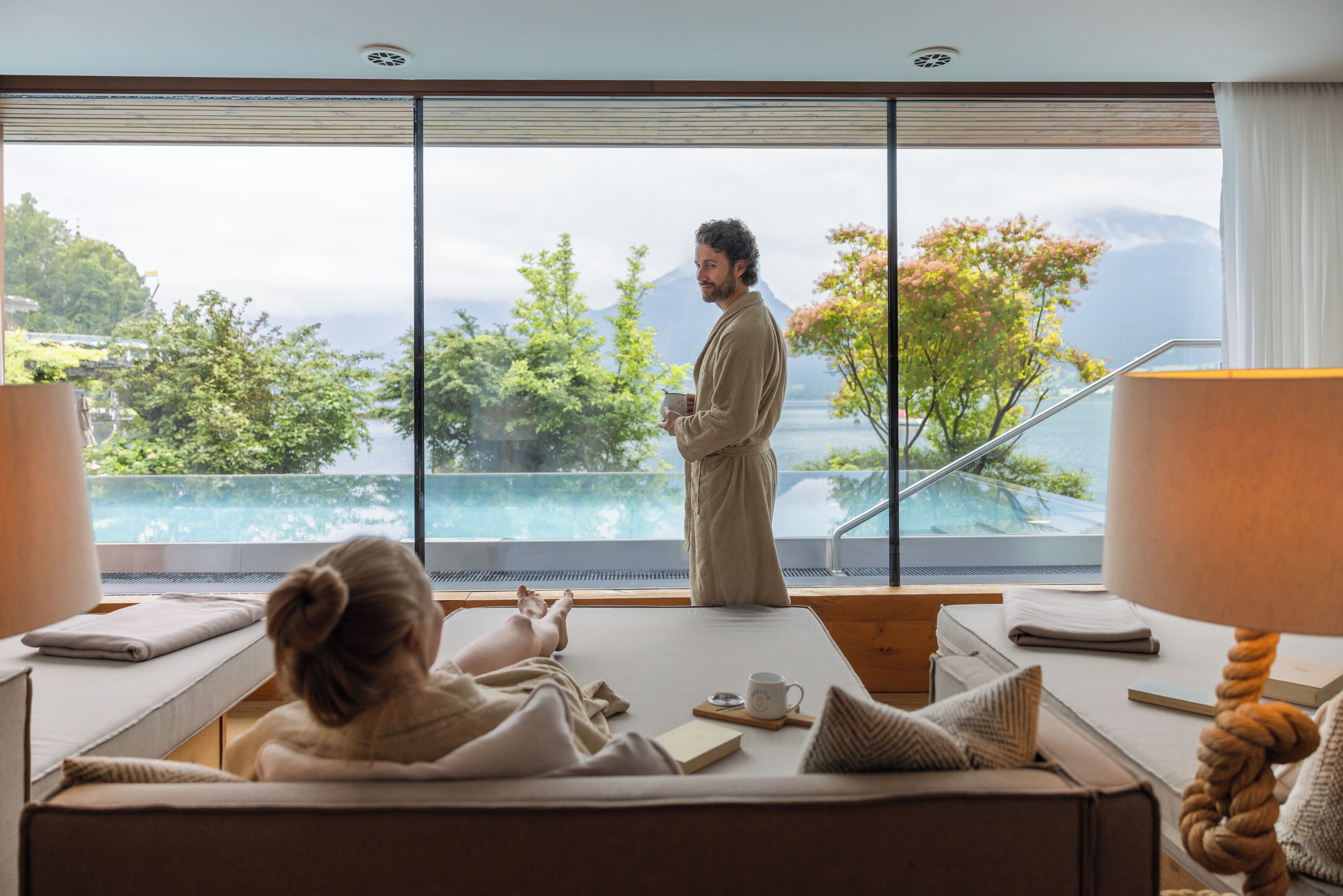 Ein Hotelzimmer mit großem Fenster und Blick auf einen Pool und Grünflächen.