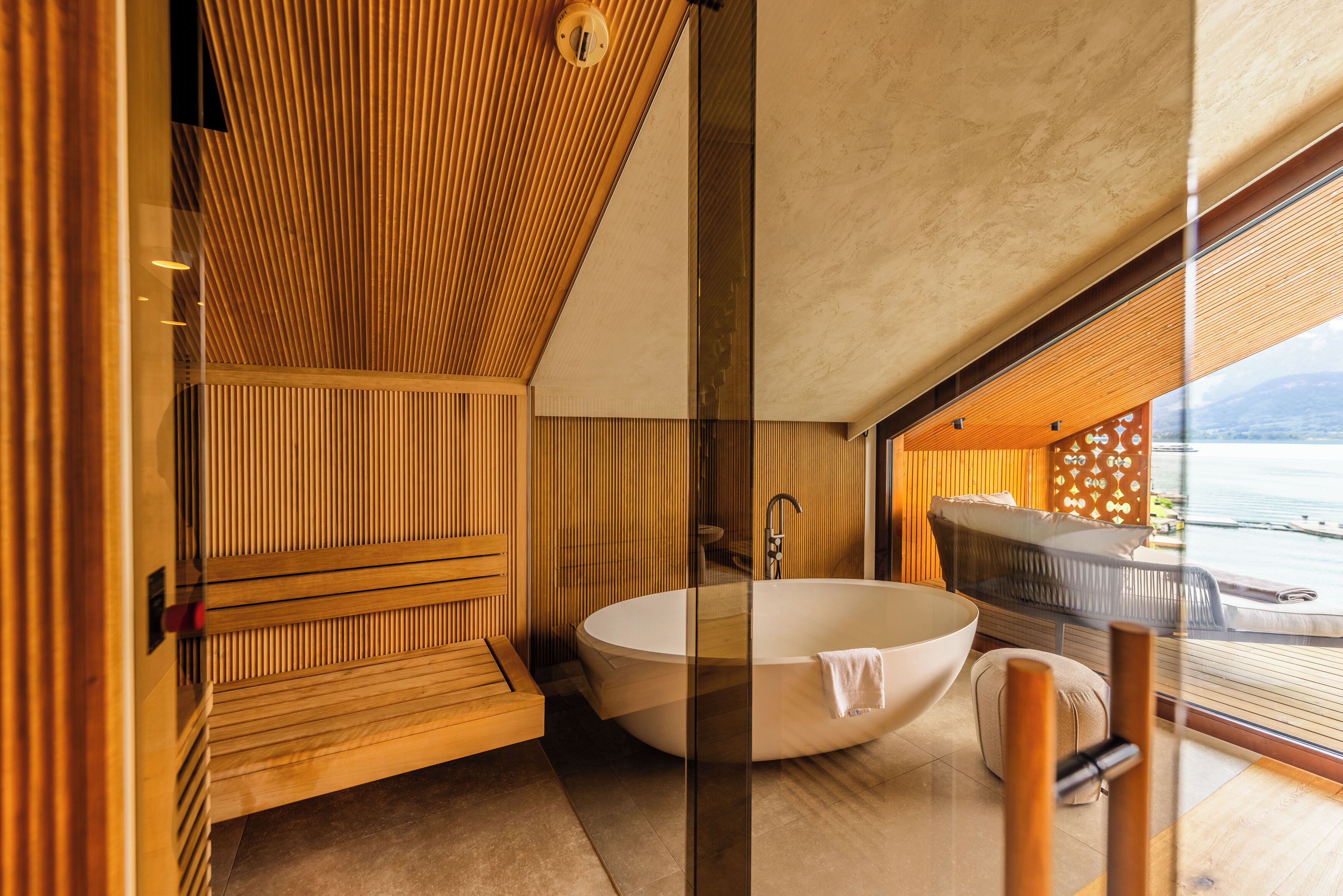Un baño moderno con una bañera independiente, paneles de madera y vista al mar.