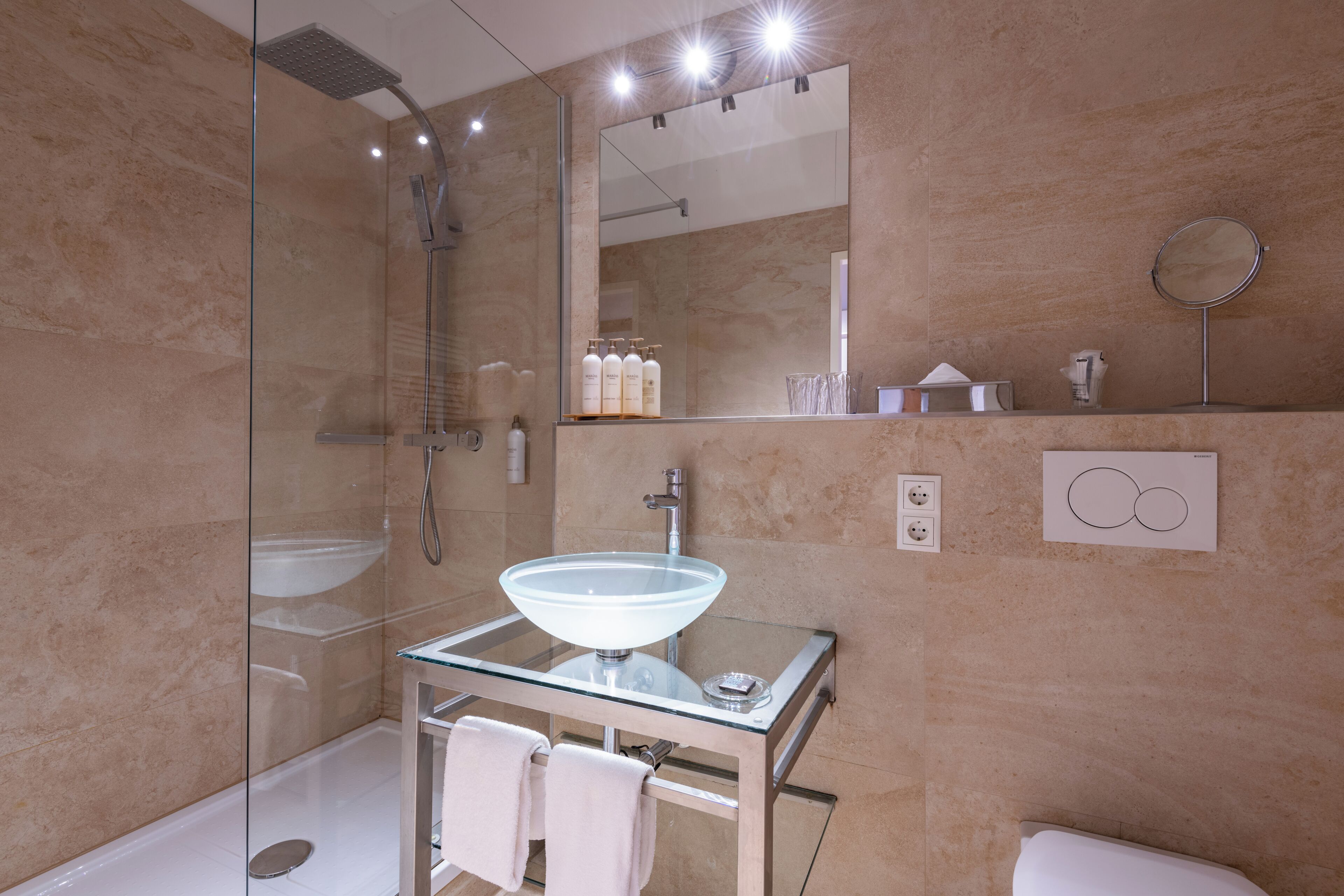 Ein modernes Badezimmer mit einer gläsernen Duschkabine, einem Waschbecken aus Glas und einem Spiegel darüber.