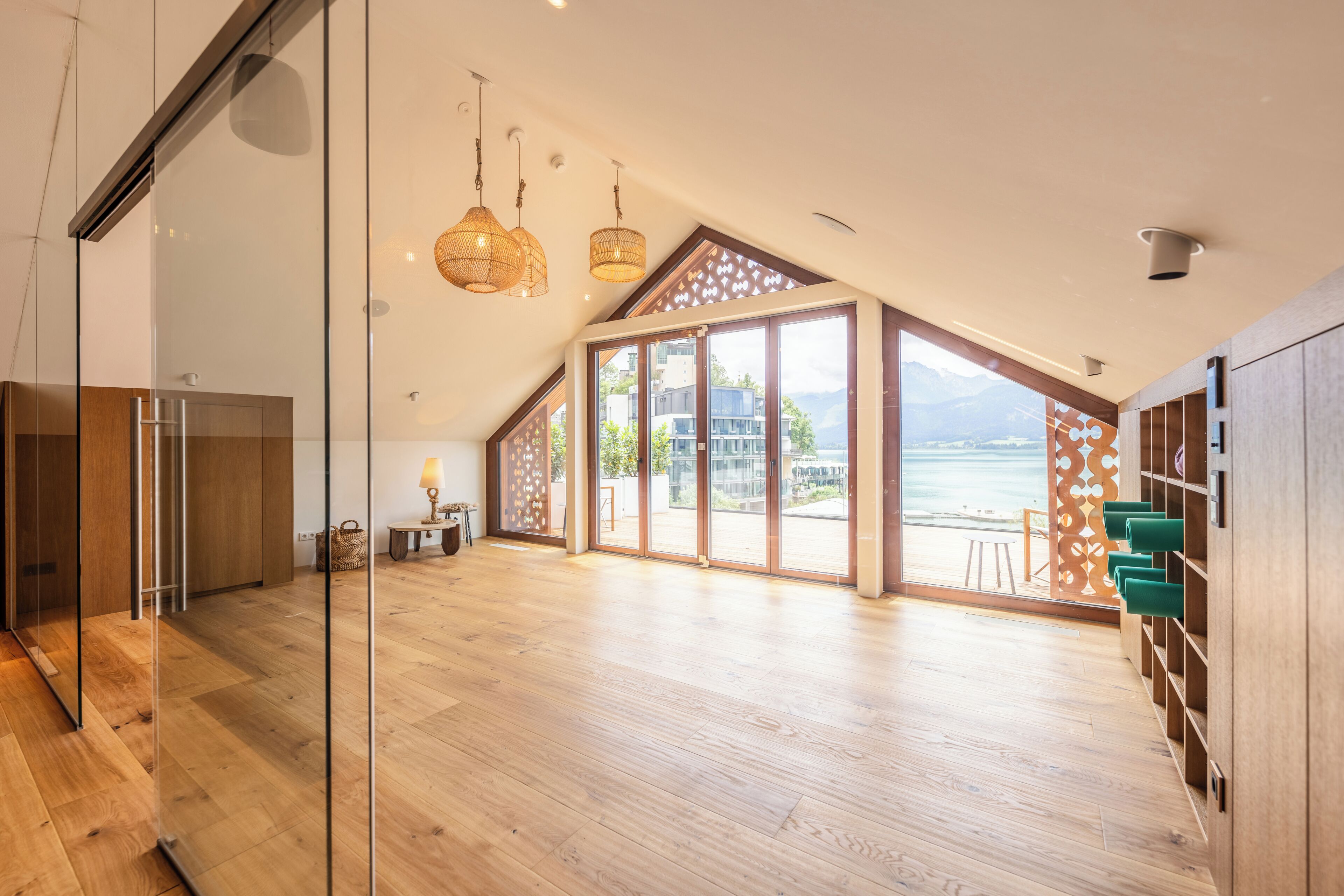A spacious room with a large glass door leading to a balcony with a view of mountains.
