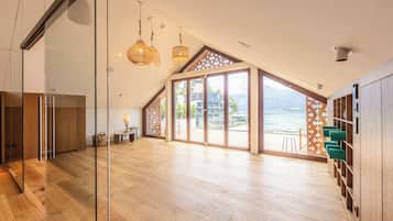 A spacious room with a large glass door leading to a balcony with a view of mountains.