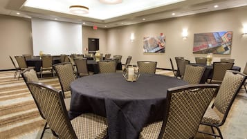 Une salle de conférence équipée d’une table ronde, de chaises, d’un écran de projection et d’œuvres d’art murales.