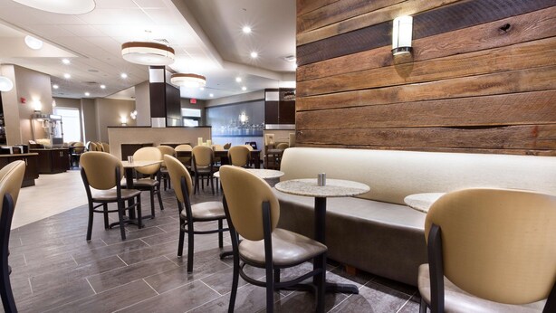 A modern restaurant with a mix of booth seating and tables, a wooden accent wall, and a tiled floor. - Drury Inn & Suites Louisville North (Louisville)