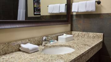 A bathroom with a granite countertop, a sink, a mirror, and a towel rack.