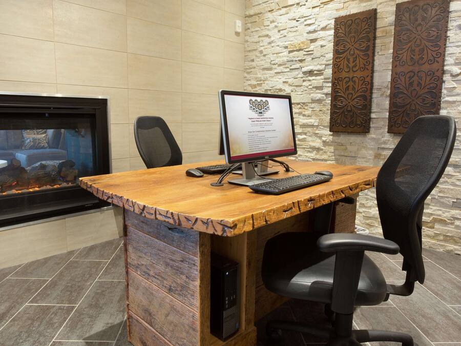 Une salle de conférence avec une table en bois, un ordinateur et deux chaises.