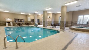 An indoor swimming pool with clear water, surrounded by lounge chairs and a sunshade. - Drury Inn & Suites Louisville North (Louisville)