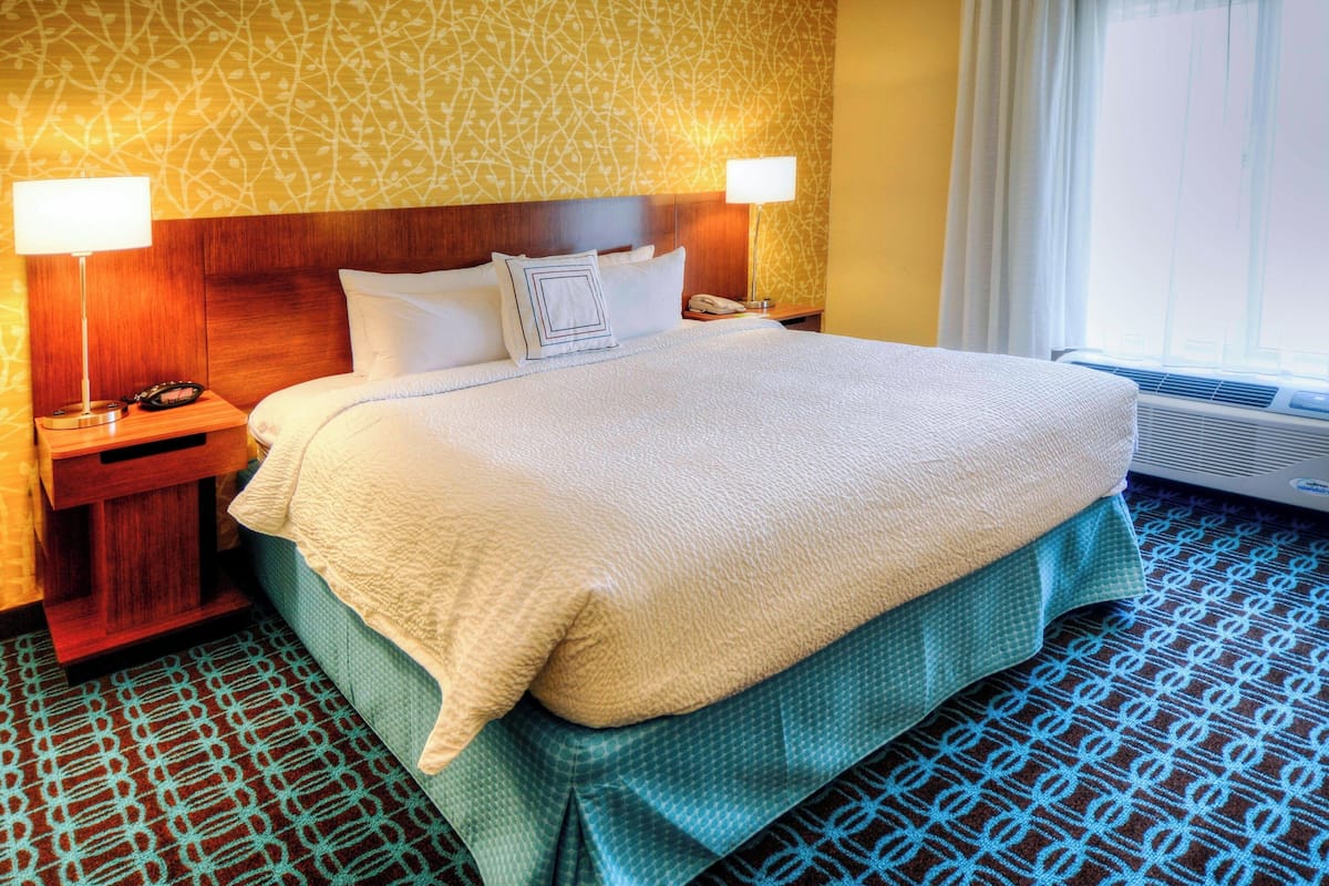 Une chambre d’hôtel avec un grand lit, deux lampes de chevet, un téléphone et un appareil de climatisation.