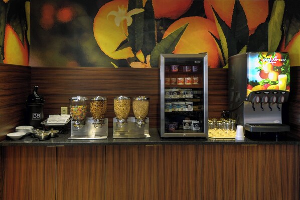 Un mostrador de buffet con un dispensador de bebidas, un refrigerador y varios recipientes de comida.