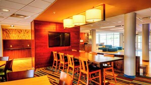 A hotel lobby with a bar area, seating, and a large TV screen. - Fairfield Inn & Suites by Marriott Princeton (Princeton)