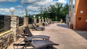 A patio with wicker lounge chairs and a stone wall. - Fairfield Inn & Suites by Marriott Princeton (Princeton)