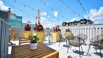 Enjoy the rooftop view of the city from this spacious outdoor space, featuring a wooden table and comfortable seating.
