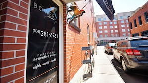 A storefront with a sign for 'Bower Bros Furnished Executive Suites' offering nightly, weekly, and monthly services. - Lester Lofts by Bower Boutique Hotels (Moncton)