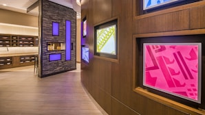 A modern hotel lobby with a wooden reception desk, a stone accent wall, and framed artwork on the walls. - Hyatt Place Cleveland / Westlake / Crocker Park (Westlake)