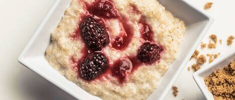 Zwei weiße, quadratische Schalen Haferflocken mit Beeren und Granola.