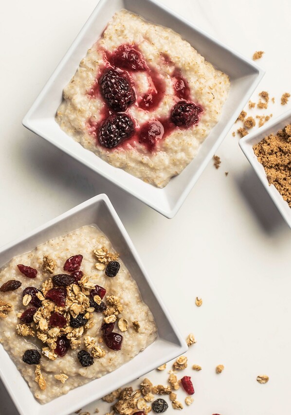 Dos tazones blancos cuadrados de avena con bayas y granola.