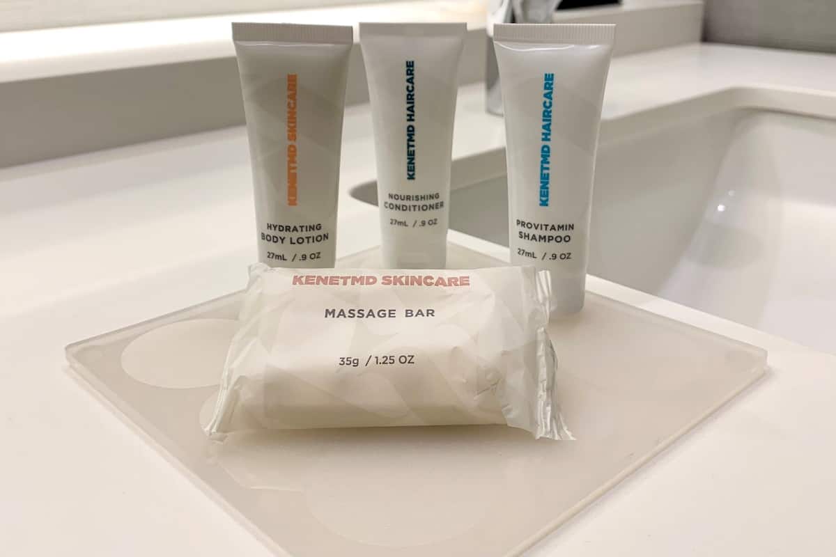 A bathroom with a white sink, three skincare products, and a massage bar.