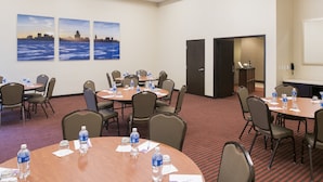 A conference room with round tables, chairs, water bottles, and a cityscape painting on the wall. - Hyatt Place Cleveland / Westlake / Crocker Park (Westlake)