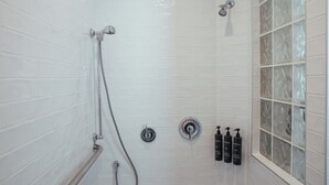 Dusche mit Handbrause, einer fest installierten Bedienblende und einem Fenster mit satiniertem Glas.