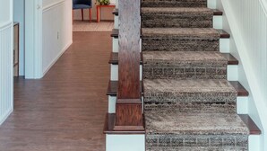 Eine Treppe mit gemustertem Teppich und Holzhandl äufen, die zu einer oberen Etage führt.
