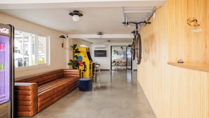 A modern interior with a long brown bench, a vending machine, and a bicycle mounted on the wall.