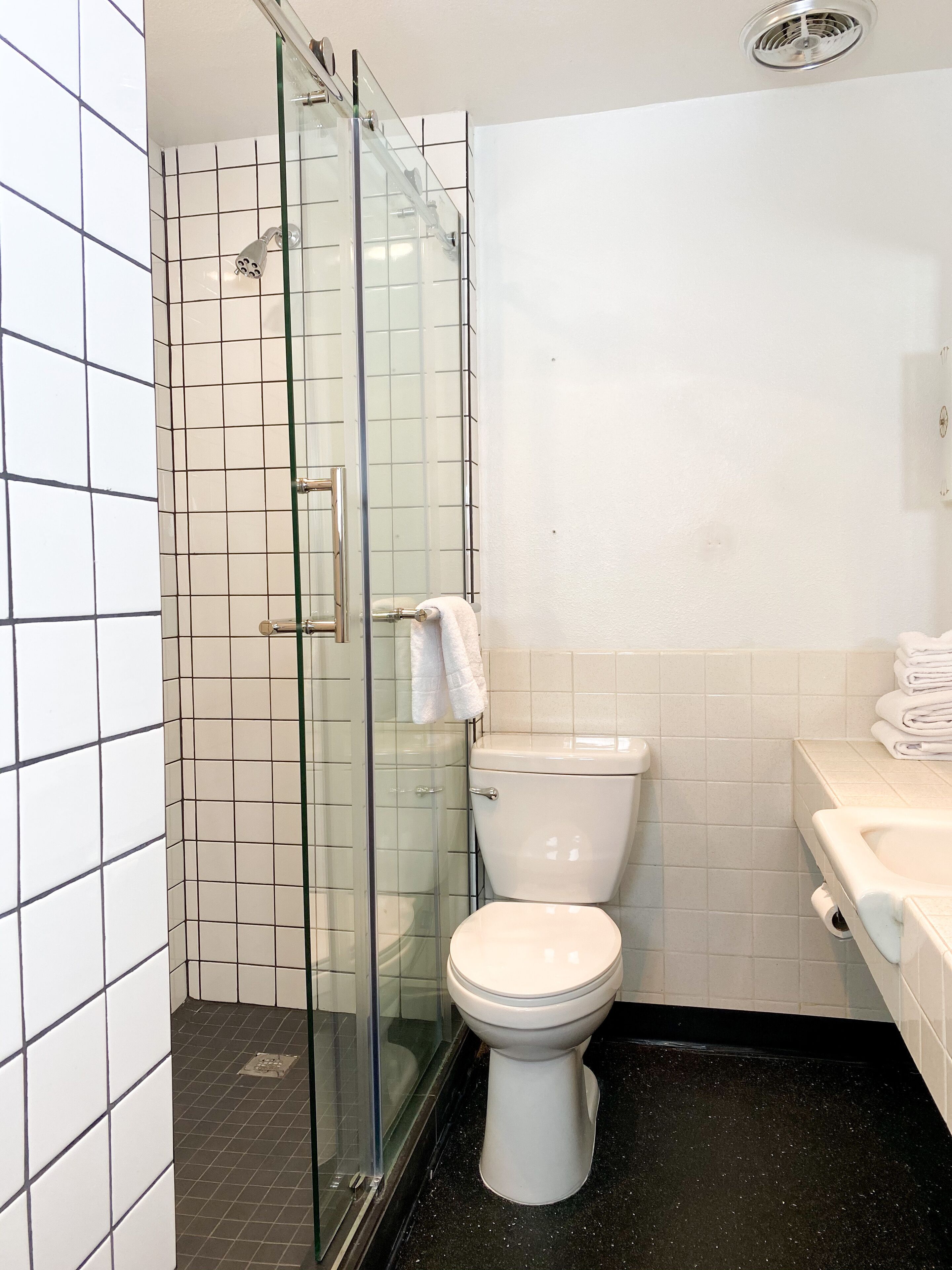 Un baño con ducha envuelta en vidrio, inodoro y lavamanos.