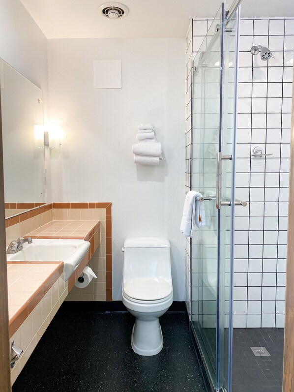 A bathroom with a sink, toilet, and glass shower enclosure.