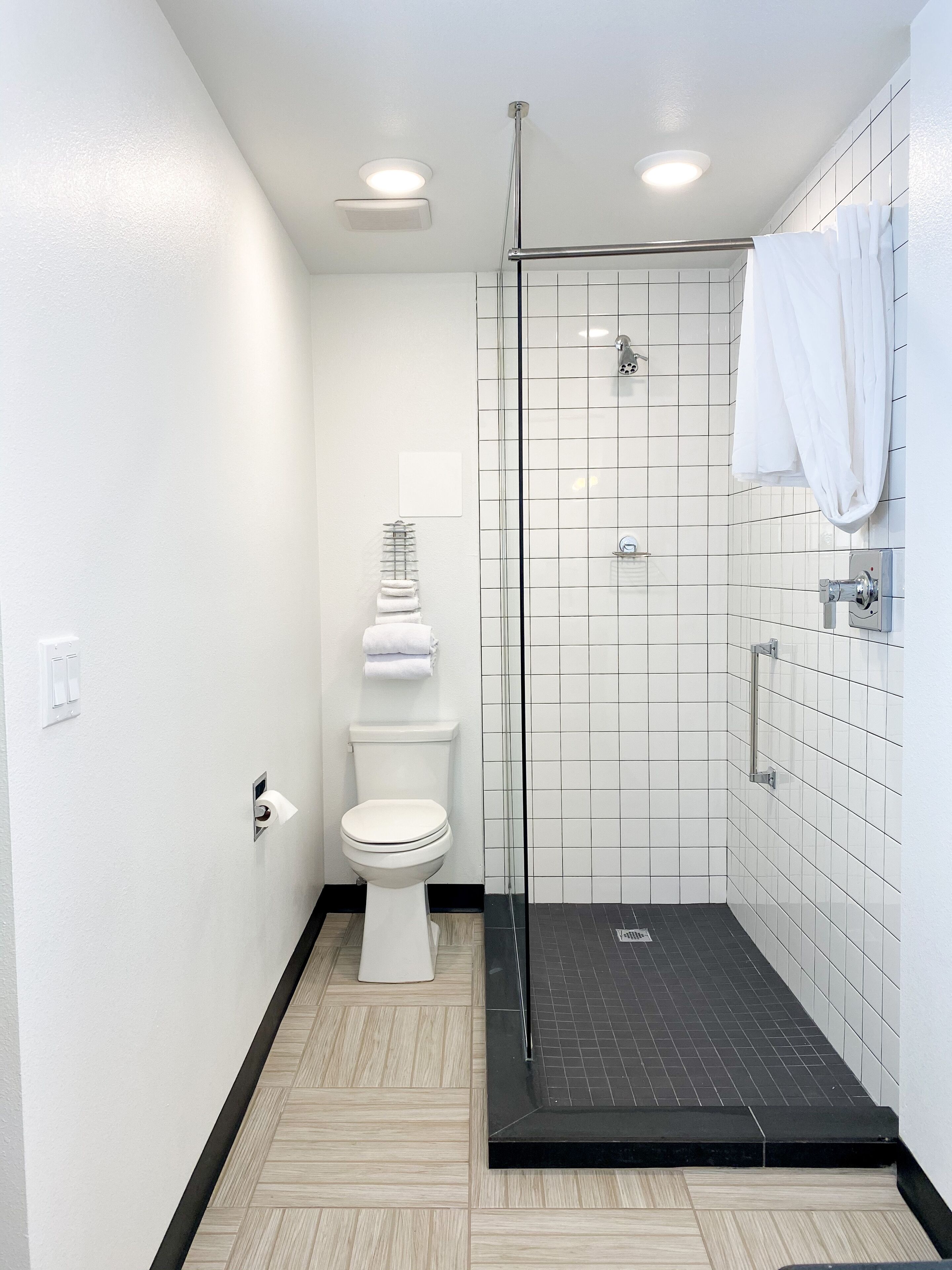 Un baño moderno con inodoro, cabina de ducha de vidrio y suelo de baldosas.