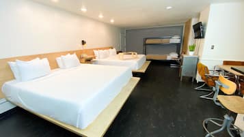 A hotel room with two beds, a desk, a chair, a television, and a small plant.