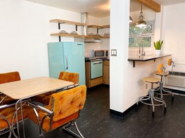 Cocina compacta con refrigerador, microondas y estufa. Hay un comedor con mesa y sillas.