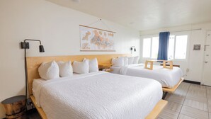A hotel room with two beds, a map on the wall, and a window with curtains.